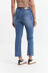 Jean straight de tiro medio, color azul denim, con corte recto y ruedo desflecado.