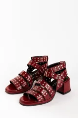 Sandalias de cuero color bordó con tres tiras horizontales sobre el empeine y pulsera al tobillo, ambas con apliques de tachas plateadas.