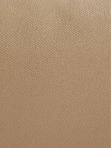 Cartera bandolera color beige con monograma CK grabado en toda la superficie. Tiene correa de cadena plateada, bolsillo externo con cierre giratorio y herrajes plateados.