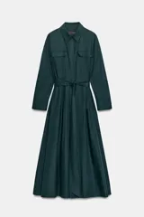 Vestido midi de estilo camisero color verde oscuro, con cuello solapa, escote en pico y cierre frontal con botones. Presenta manga larga, bolsillos laterales ocultos, solapas decorativas en el pecho y cinturón de lazada en el mismo tejido.