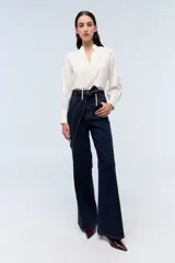 Camisa color crema a rayas verticales finas, con cuello mao con lazos para atar, escote en V y mangas largas con puños abotonados.