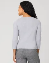 Cardigan blanco de tejido liviano con trama en relieve, cuello a la base y cierre frontal con botones a tono. Presenta mangas tres cuartos.
