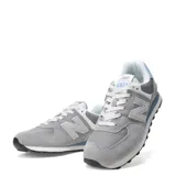 Championes urbanos New Balance modelo 574, color gris con detalles en celeste y blanco. Confeccionados en una combinación de gamuza y material sintético, presentan el logo N en los laterales y entresuela con tecnología ENCAP.