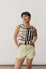 Short gris claro de tiro alto con costuras pespunteadas en contraste y bolsillos traseros amplios. Presenta una etiqueta de cuero rojo en la parte posterior de la cintura.