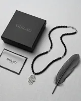 Collar de acero con cuentas de cristal negro y dije central en forma de mano de Hamsa con detalles grabados.