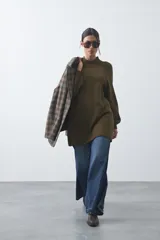 Vestido corto de punto en color beige, con cuello alto acanalado, mangas largas con puños ajustados y diseño holgado.
