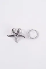 Set de dos anillos de color plateado. Uno de los anillos presenta un diseño de estrella de mar con textura rugosa, mientras que el otro es un anillo fino con diseño de cadena trenzada.