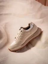 Sneaker urbana de edición limitada inspirada en Star Wars, color off-white con detalles en plateado. Presenta el texto 'JOIN THE RESISTANCE' en el lateral, parche de Star Wars en la lengüeta y dije metálico en los cordones. Suela de plataforma en tono arena con base de goma dentada.