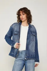 Chaqueta de jean azul con corte oversized, bolsillos con solapa en el frente, cierre metálico y detalles de desgastado suave.