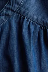 Blusa de denim de algodón suave, de color azul, con cuello mao, botonadura frontal y mangas cortas abullonadas.