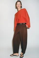 Pantalón tiro bajo color marrón, de corte globo y pernera recta con raya marcada al frente. Incluye trabillas y un cinturón marrón oscuro con hebilla metálica.