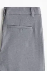 Pantalón sastrero gris de tiro alto, corte ajustado y piernas acampanadas, con trabillas para cinto y bolsillos traseros insertados.