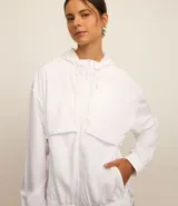 Campera deportiva cortaviento color blanco, con capucha ajustable, cierre frontal por cremallera y diseño de corte holgado. Incluye saquito para guardar.