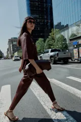 Pantalón tobillero de tiro medio color marrón oscuro, con cintura elástica ajustable con cordón y herretes dorados. Incluye bolsillos delanteros y bolsillos de plastrón en la espalda.