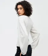 Blusa de algodón color beige con cuello redondo y mangas largas amplias de corte holgado. Presenta un diseño minimalista con costuras sutiles y ajuste regular al cuerpo.