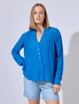 Blusa azul de gasa marca Zac & Rachel, con cuello a la base, escote en V y botones. Delantera con detalle plisado y largo de manga regulable con presilla y botón.