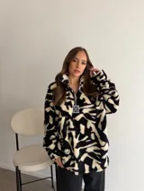 Buzo de peluche con estampado animal print de leopardo, cuello alto con cierre frontal parcial y tirador metálico decorativo.