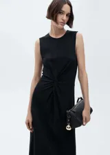 Vestido midi sin mangas de color negro, con cuello redondo y detalle drapeado en la cintura que crea un efecto de nudo frontal. Presenta un diseño recto y minimalista.