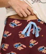 Conjunto de pijama compuesto por una remera de manga corta color crema con estampa frontal de Stitch y un short color bordó con estampado integral de Stitch. Ambas prendas están confeccionadas en viscosa con elastano.