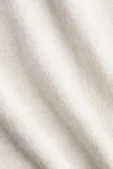 Buzo de tejido suave color beige, con cuello redondo acanalado, hombros caídos, mangas largas y puños y bajo en punto acanalado.