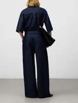 Pantalón de denim azul marino, tiro alto, con pinzas delanteras, canesú trasero y pierna ancha. Incluye cinturón de lazo del mismo tejido.