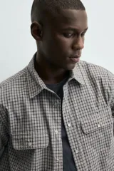 Camisa de corte regular fit confeccionada en tejido de algodón con estampado de cuadros. Presenta cuello solapa, manga larga con puños abotonados, cierre frontal de botones y dos bolsillos de plastrón con solapa en el pecho.