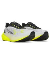 Championes de running Under Armour modelo Velociti Distance, con diseño aerodinámico en color blanco, detalles en negro y suela de espuma HOVR+ en color amarillo neón.