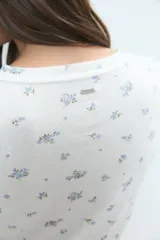 Pijama de dos piezas compuesto por una remera de manga larga con botones frontales y un short de tiro alto, ambos confeccionados en tejido acanalado con estampado floral pequeño.