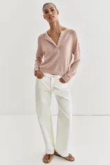 Sweater de punto color beige con cuello redondo, manga larga y cierre frontal parcial con botones. Presenta terminaciones en rib en cuello, puños y dobladillo.