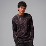 Camiseta de manga larga Jordan con cuello redondo y ajuste regular. Presenta un estampado tipo camuflaje abstracto en tonos oscuros con el logo Jumpman en color naranja en el centro del pecho.