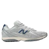 Championes New Balance modelo 204L, de estilo running retro con diseño multicapa. Presentan una combinación de tonos grises en la capellada de gamuza y malla, con el logo N en azul oscuro y detalles en el talón. La suela es de EVA con diseño inspirado en los años 2000.