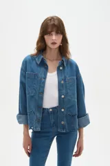 Sobrecamisa de jean azul con cierre frontal de botones metálicos, bolsillos frontales y detalle de bordado inglés en el ruedo.
