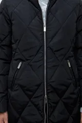 Campera acolchada de corte largo con diseño capitoneado en forma de rombos, cierre frontal con cremallera y capucha integrada.