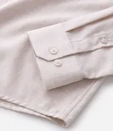 Camisa de manga larga con cuello inglés y cierre frontal de botones, confeccionada en tricolina de algodón color beige.