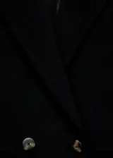 Abrigo midi de corte recto confeccionado en tejido mezcla de lana. Presenta cuello con solapas de muesca, cierre frontal de doble botonadura y dos bolsillos laterales con solapa. Incluye forro interior y mangas largas.