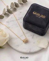 Collar de acero con baño de oro, compuesto por una cadena fina y un dije central formado por tres anillos circulares entrelazados con incrustaciones de circonias.