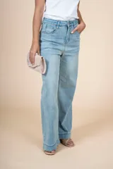 Jean de tiro alto con corte recto y silueta amplia, confeccionado en denim de lavado claro. Presenta cierre frontal con botón y bolsillos laterales y traseros.