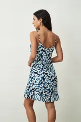 Vestido corto sin mangas con tirantes finos, escote redondo y diseño estampado en tonos azul, negro y blanco, con detalle de volados en el borde inferior.
