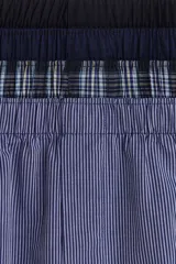 Pack de cuatro calzoncillos tipo boxer de tela de algodón suave, con cintura elástica y cierre de botones. El set incluye un modelo liso azul marino, uno con microestampado, uno a cuadros y uno a rayas verticales.