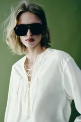 Camisa blanca ZARA Woman Collection de 100% seda, con escote en V ajustable con cordones entrelazados y manga larga con puños rectos.