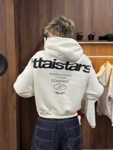 Hoodie de color blanco con capucha, diseño de corte holgado y estampado gráfico en la espalda con tipografía negra.