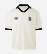 Remera de punto con textura calada, corte boxy y cuello polo en contraste. Presenta escote en V, mangas cortas con terminación en contraste y bordados decorativos en el pecho.
