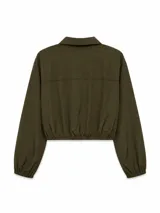 Campera corta de tela técnica con acabado ligeramente arrugado, color beige. Presenta cuello camisero, cierre frontal con botones a presión, mangas largas con puños elásticos y ruedo ajustable con cordón.