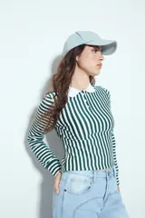 Remera de manga larga a rayas verticales verdes y blancas, con cuello polo y cierre frontal de botones. Presenta un diseño ajustado al cuerpo.