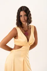 Vestido largo de tela sedosa color durazno, con escote en V, aberturas laterales en la cintura (cut-out) y tajos laterales en la falda. Posee espalda regulable con lazo y elástico.