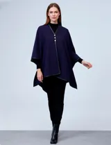 Ruana negra de tejido suave, con cierre frontal de botones metálicos y ribetes de cuero sintético en los bordes.