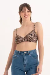 Top de bikini con estampado animal print en tonos beige y negro, con breteles finos y diseño cruzado en el centro del busto.