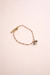 Pulsera de cadena dorada con dijes de piedras naturales y cuentas de colores. Presenta un diseño delicado con eslabones finos y cierre de mosquetón.