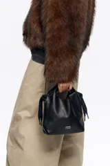 Bolso de hombro Bimba y Lola tamaño mini, de estructura blanda y color marrón oscuro, confeccionado en piel vacuna. Presenta asas de mano de piel y una correa extraíble, con detalles metálicos y logo de la marca en el frente.