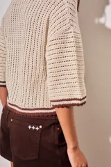 Sweater de tejido abierto de algodón, color beige, con cuello polo, mangas cortas y detalles en color marrón oscuro en los bordes y puños.